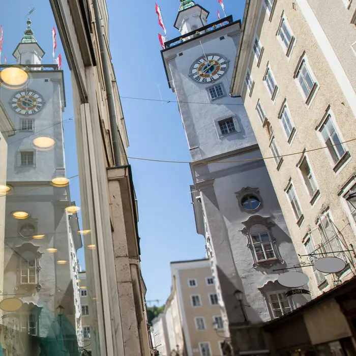 Kleine Gasse mit Shops. Im Hintergrund steht ein hoher Turm.