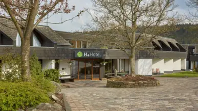 Hotelauffahrt mit Bäumen und Eingangsbereich.