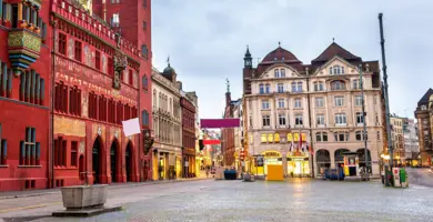 Rotes Rathaus von Basel auf der linken Seite und Vorplatz mit Geschäften im Hintergrund.