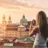 Blick auf den Dom zu Salzburg während des Sonnentuntergangs. Im Vordergrund steht eine Frau und macht ein Foto.
