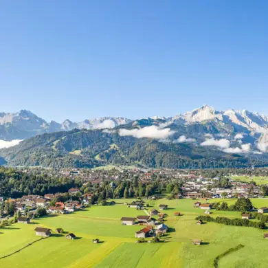 Blick auf Garmisch-Partenkirchen und die Wiesen von oben im Sommer. Im Hintergrund ist das Gebirge.