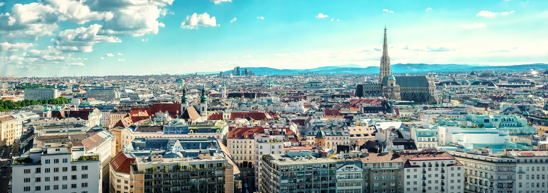 Blick über die Stadt Wien. Im Hintergrund sind Berge.