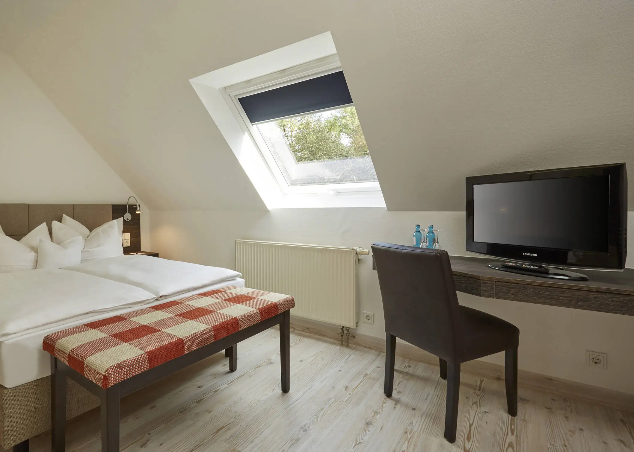 Hotel room in the attic with a double bed and a desk.