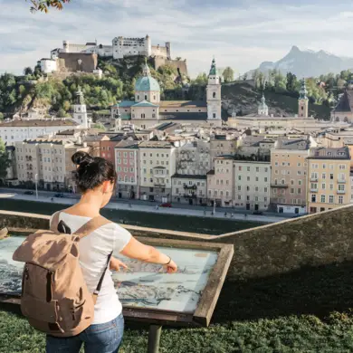 Woman stands at the city map and looks at the panorama