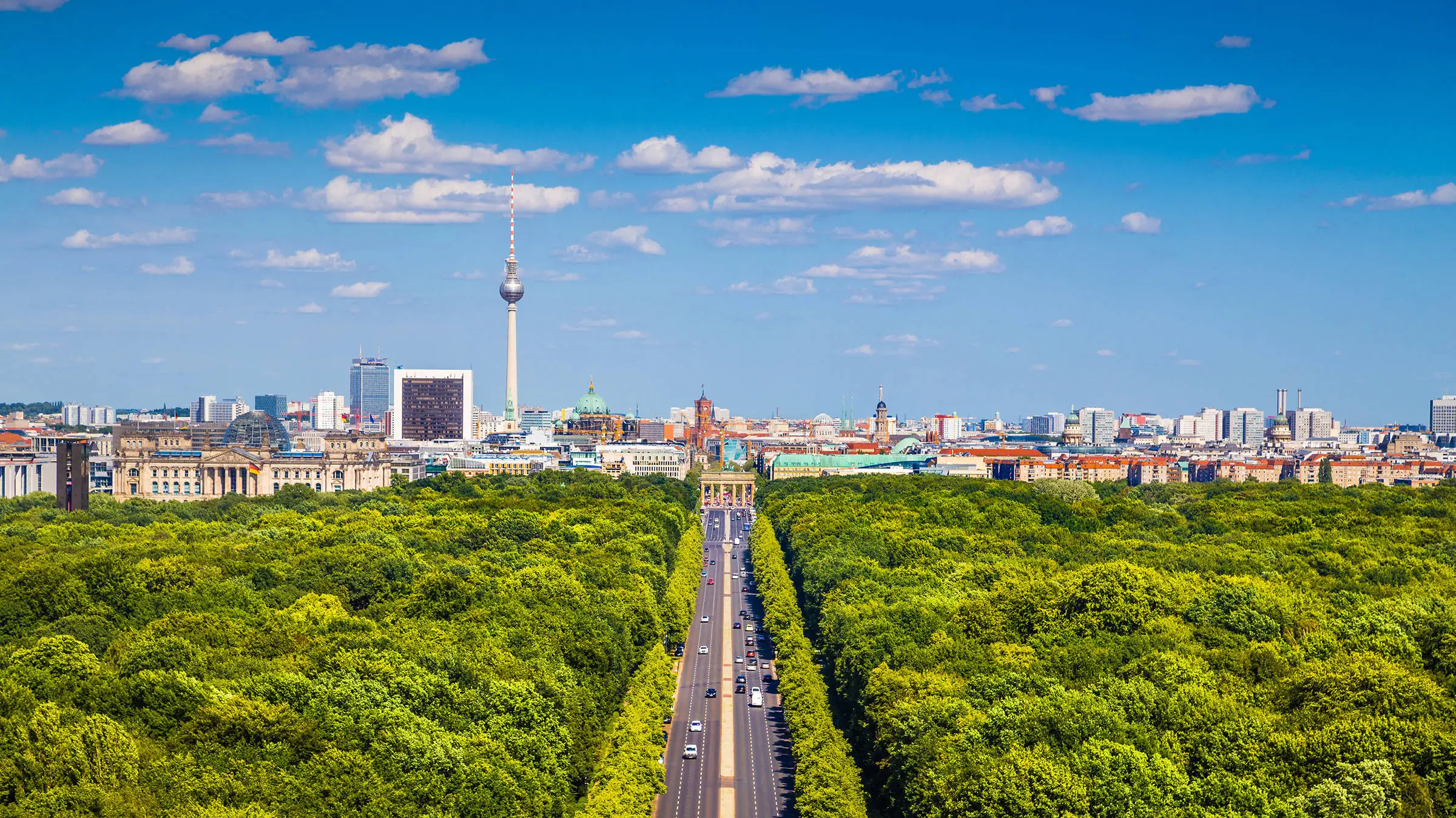 Blick über den Tiergarten auf die Skyline von Berlin. In der Mitte steht das Brandenburger Tor.