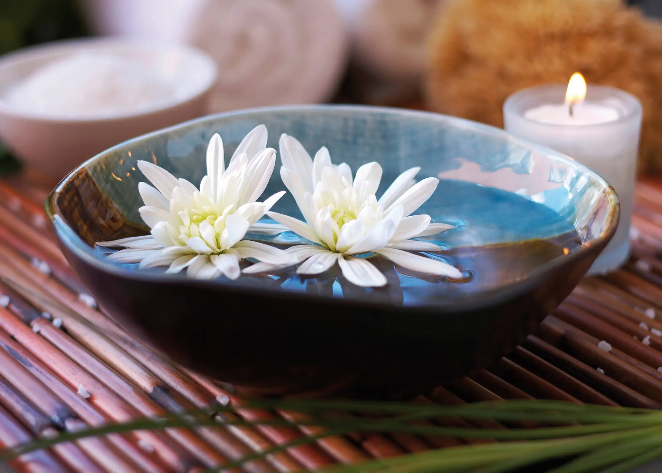 Gros plan d'un brûle-parfum avec deux fleurs blanches.