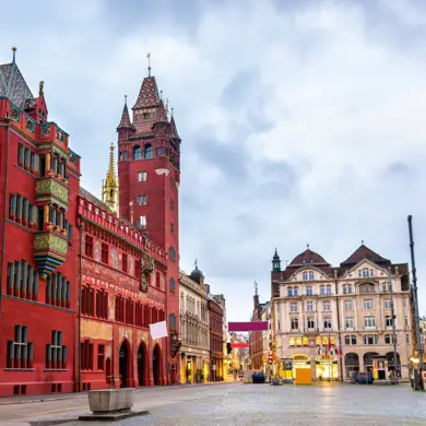 Rotes Rathaus von Basel auf der linken Seite und Vorplatz mit Geschäften im Hintergrund.