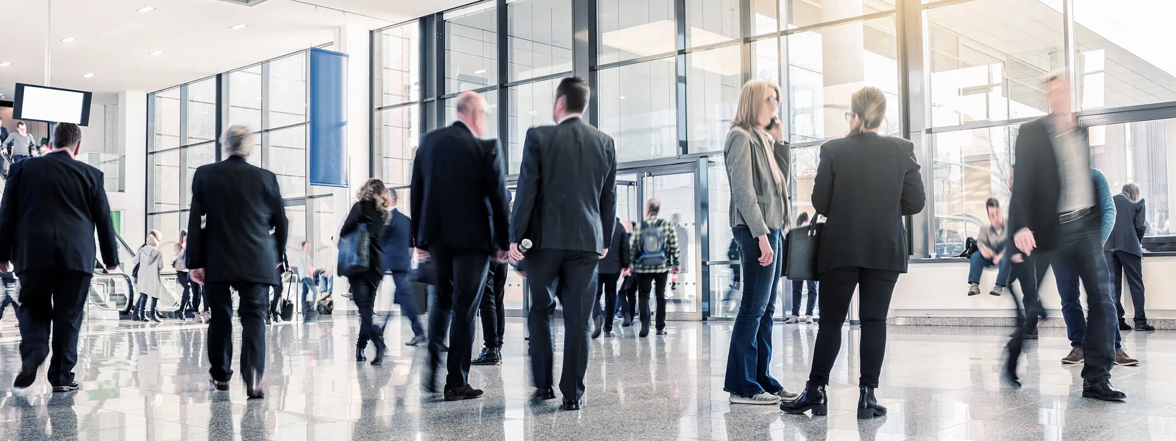 Viele Menschen im ANzug stehen in einer großen Halle.