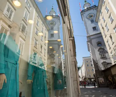 Kleine Gasse mit Shops. Im Hintergrund steht ein hoher Turm.