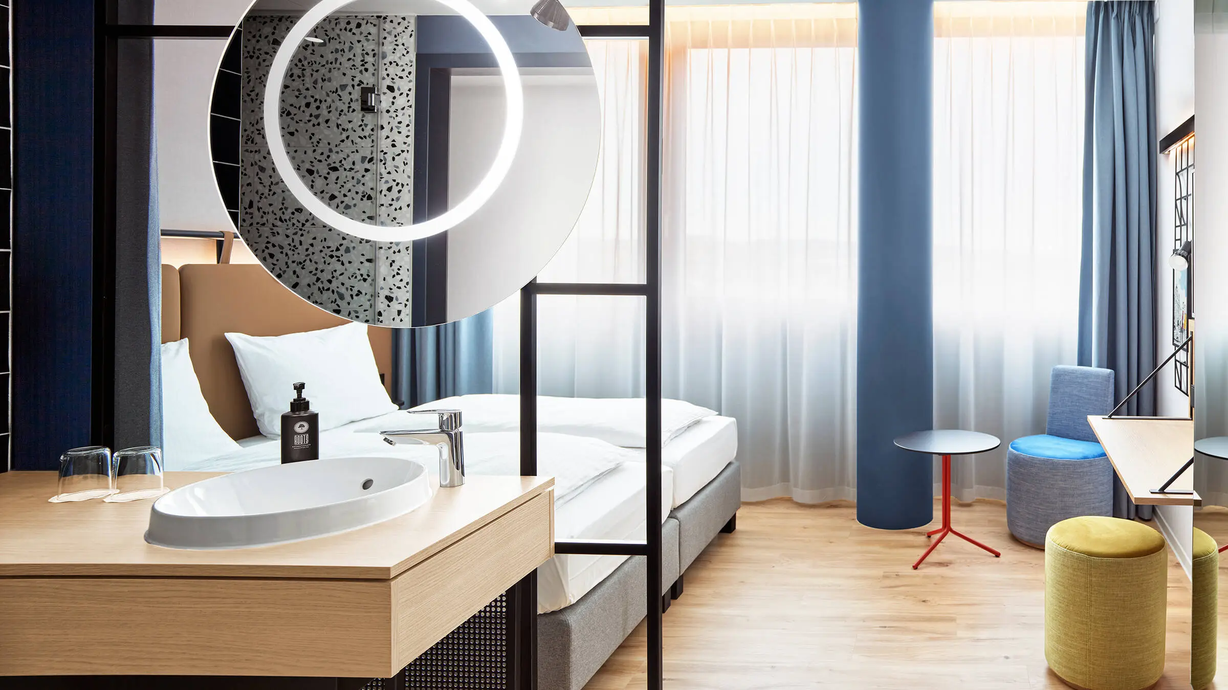 Hotelzimmer mit Doppelbett. In der Mitte steht eine kleine Sitzecke.