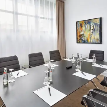 Konferenztisch im Konferenzraum. An der Wand hängt ein Bild.