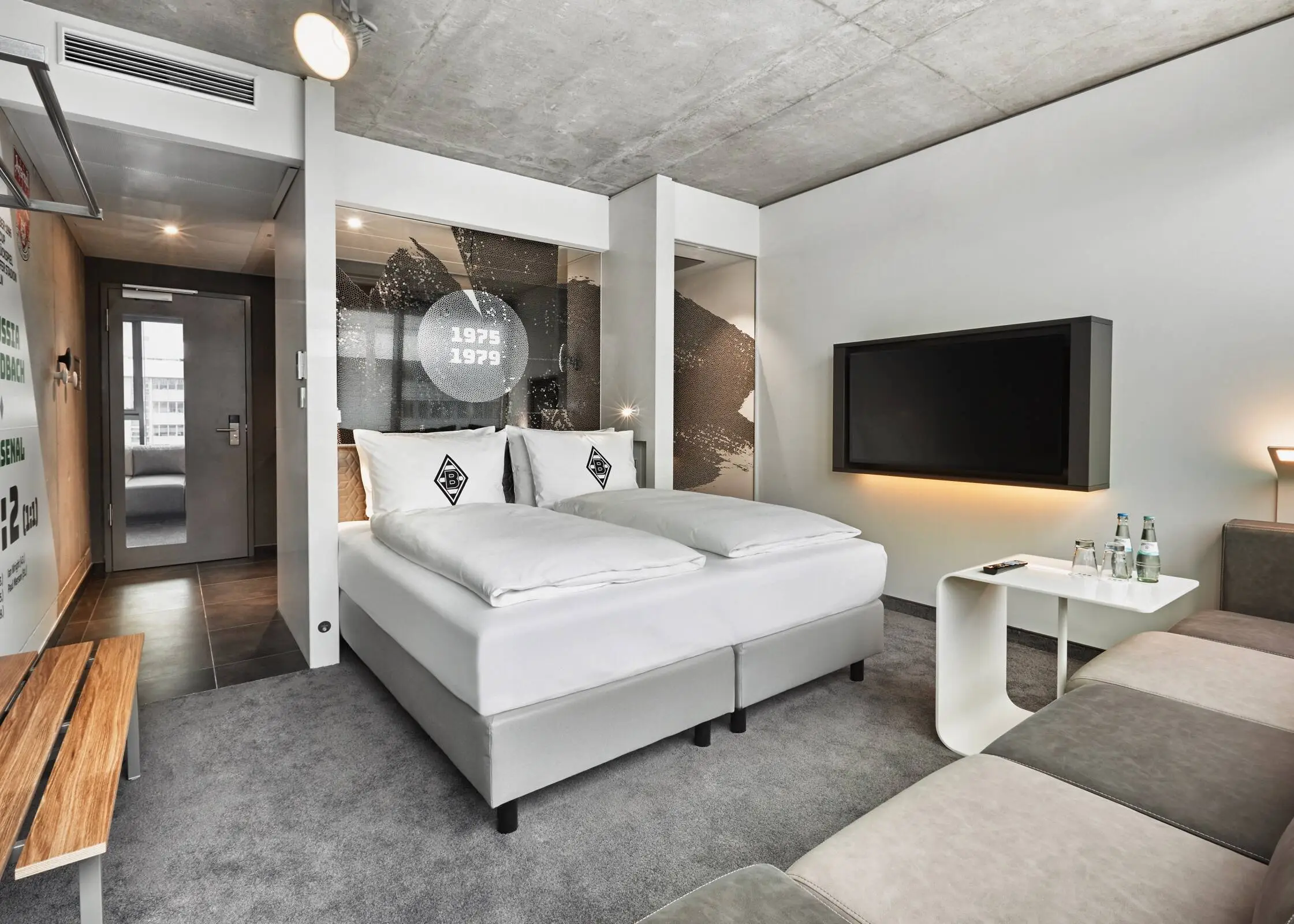 Hotelzimmer im Stil einer Umkleidekabine. In der Mitte steht ein Doppelbett.