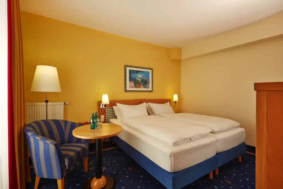 Habitación de hotel con una cama doble y un sillón al lado.