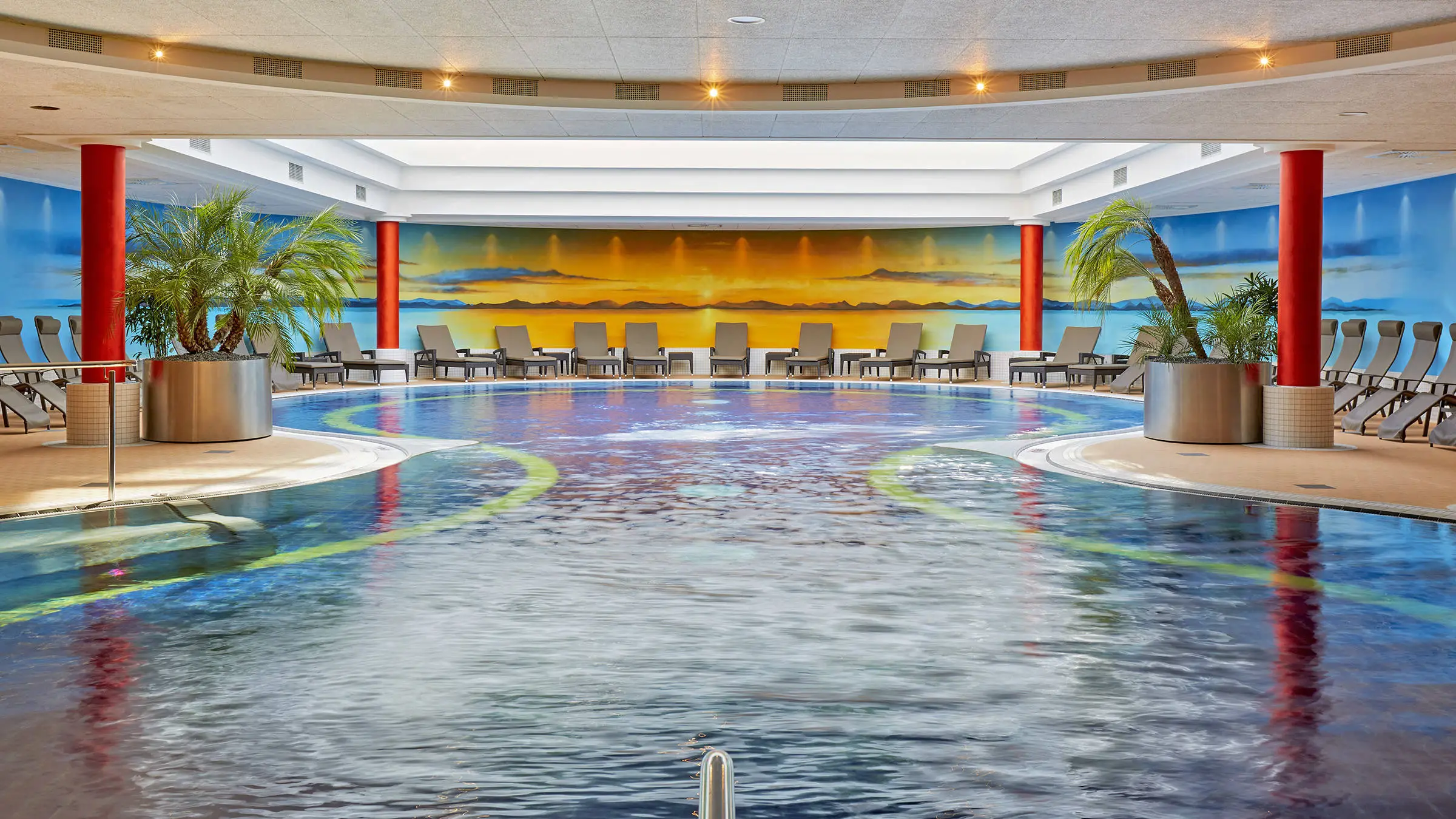 Piscina con un gran vaso y tumbonas en el borde.