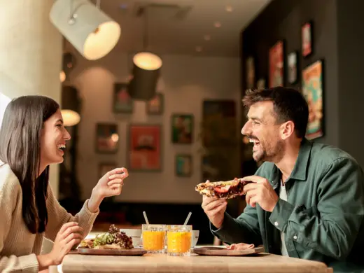 Ein Paar sitzt beim Frühstück und lacht.