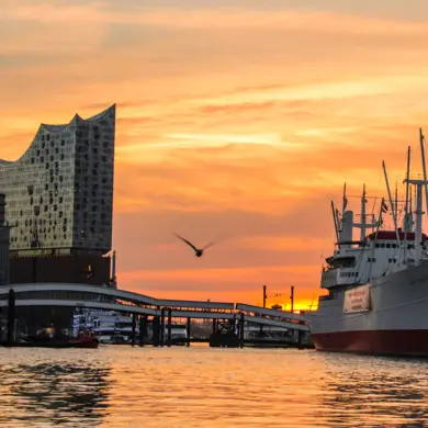 Blick suf die Elbe während des Sonnenuntergangs. Links steht die Elbphilharmonie, Rechts ein Schiff.