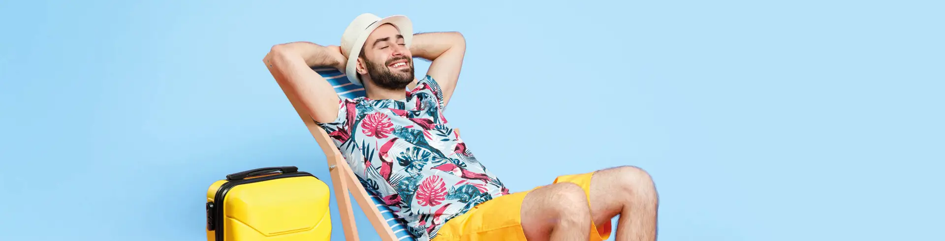 Mann im Sommeroutfit liegt auf einem Liegestuhl vor einem blauen Hintergrund. 