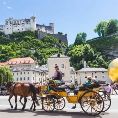 Carruaje dorado con dos caballos frente al castillo