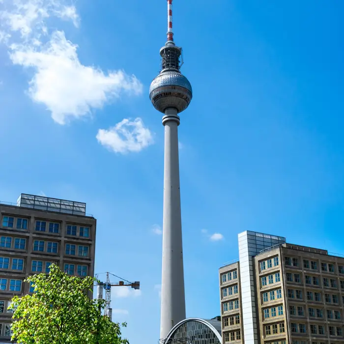 Belebter Alexanderplatz am Tag mit Blick auf den Fernsehturm. Im Vordergrund steht die Weltzeituhr.