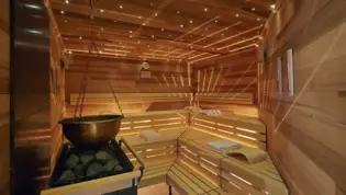 Pequeña sauna de esquina desde el interior con una parrilla de infusión de sauna.