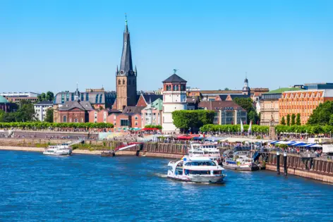 Blick vom Rhein auf die Rheinuferpromenade, die Altstadt und auf Boote.