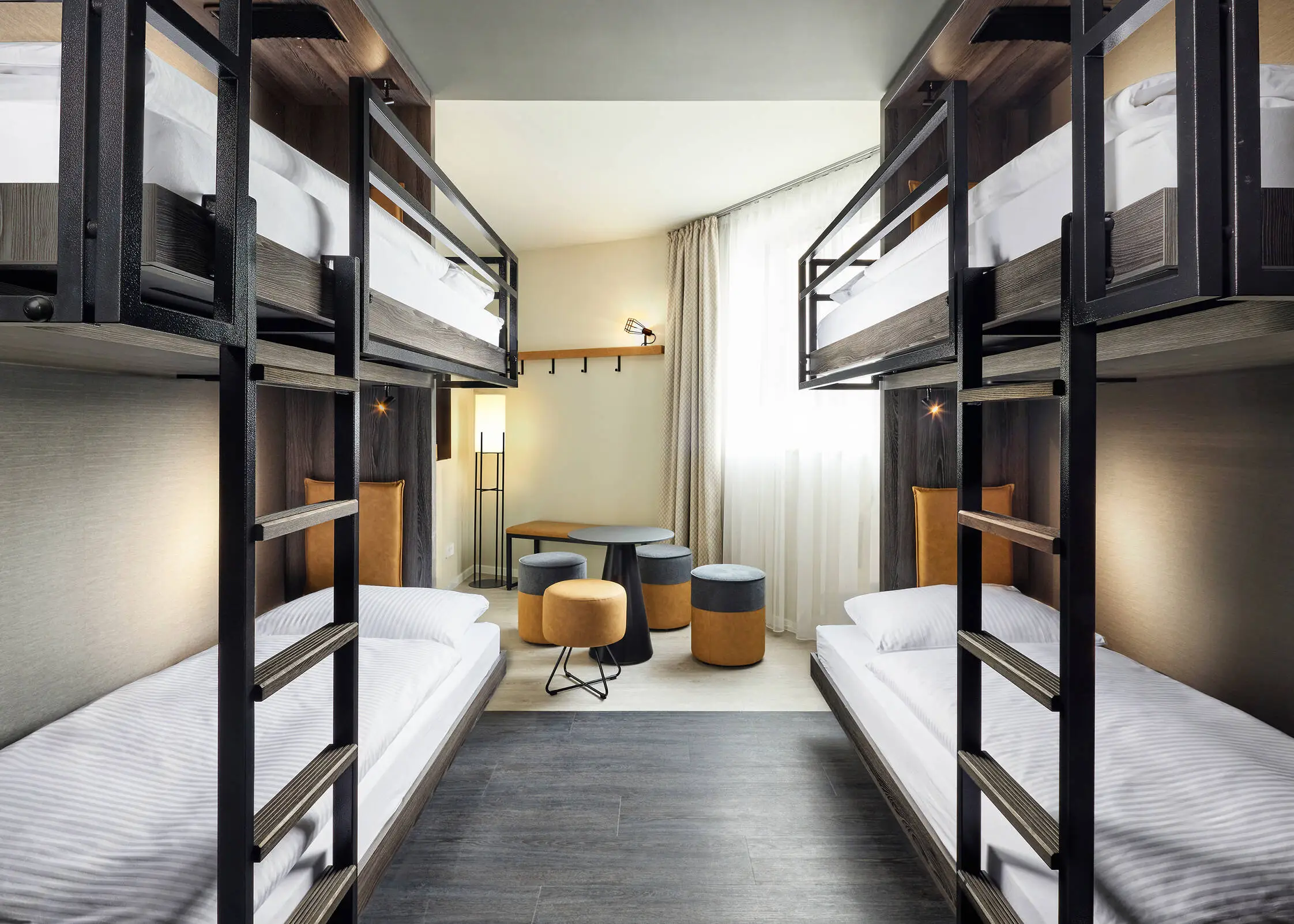 Hotelzimmer mit zwei Etagenbetten. In der Mitte steht eine kleine Sitzecke.