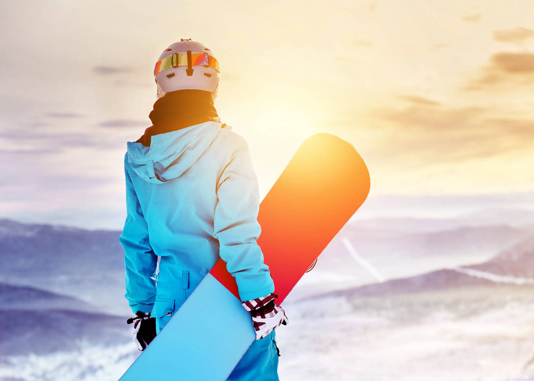 A snowboarder is standing with his snowboard in his hand.