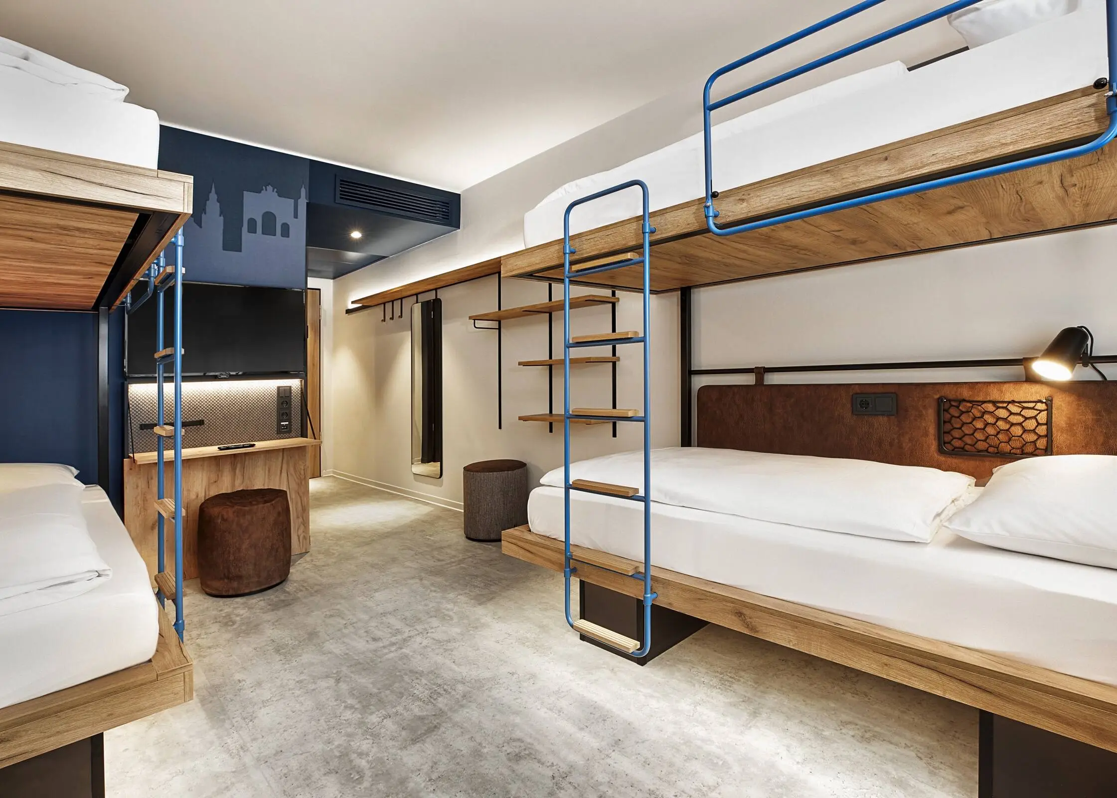 Habitación de hotel con literas. La habitación está decorada en tonos azul oscuro y marrón.